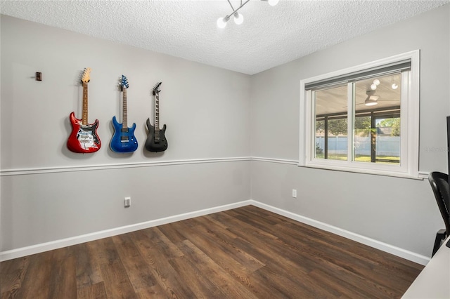 unfurnished office featuring a textured ceiling, baseboards, and wood finished floors