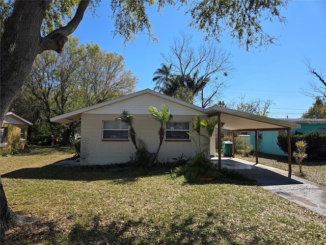 exterior space with an attached carport, concrete block siding, concrete driveway, and a front lawn