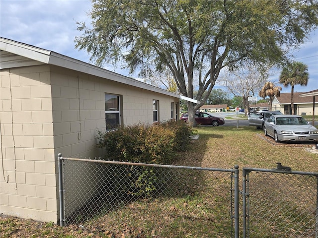 view of side of property featuring a gate, concrete block siding, and fence