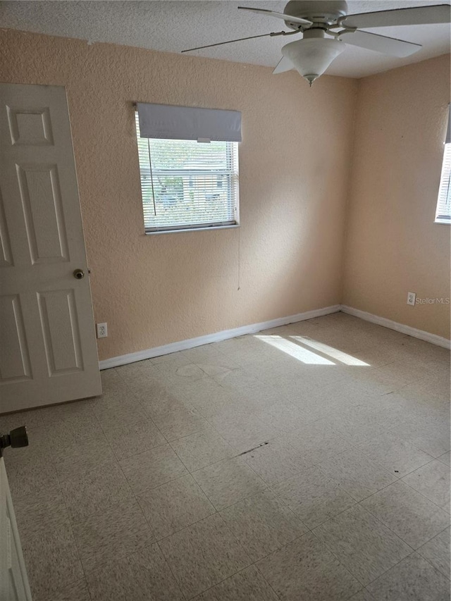 empty room featuring tile patterned floors, ceiling fan, and baseboards