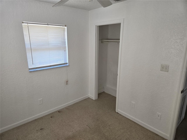 unfurnished bedroom featuring a closet, carpet flooring, baseboards, and a textured wall