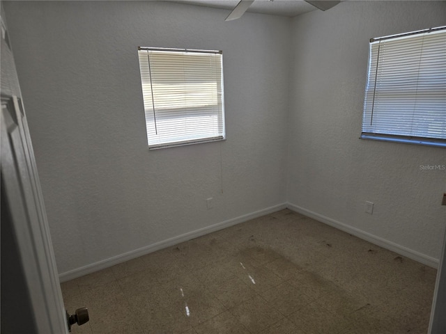 empty room featuring tile patterned floors, a ceiling fan, and baseboards