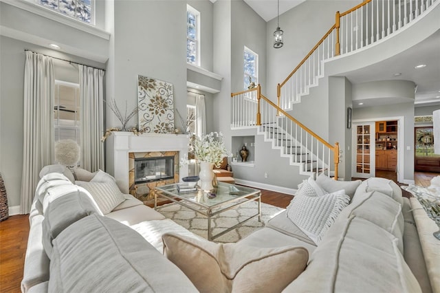 living area with a tile fireplace, stairway, baseboards, and wood finished floors