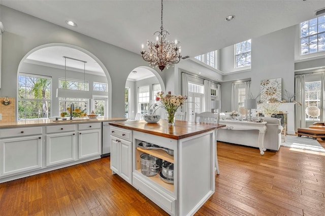 kitchen with white cabinets, hardwood / wood-style flooring, butcher block counters, open floor plan, and a sink