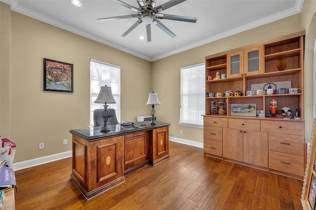 home office featuring dark wood-type flooring, crown molding, baseboards, and a ceiling fan