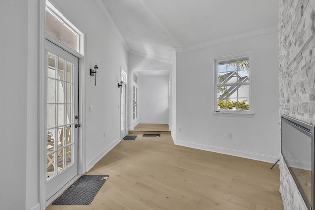 interior space with light wood-style floors, vaulted ceiling, crown molding, and baseboards