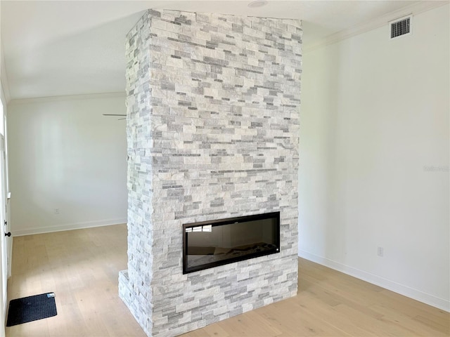 interior details with ornamental molding, a fireplace, baseboards, and wood finished floors