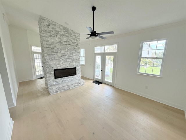 unfurnished living room with french doors, a fireplace, light wood-style floors, ornamental molding, and baseboards