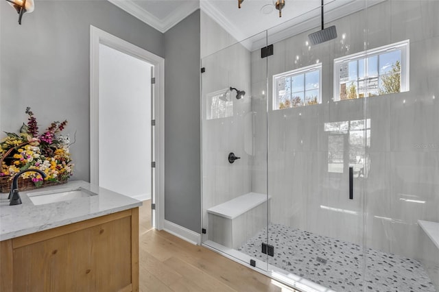 bathroom featuring wood finished floors, vanity, baseboards, ornamental molding, and a shower stall