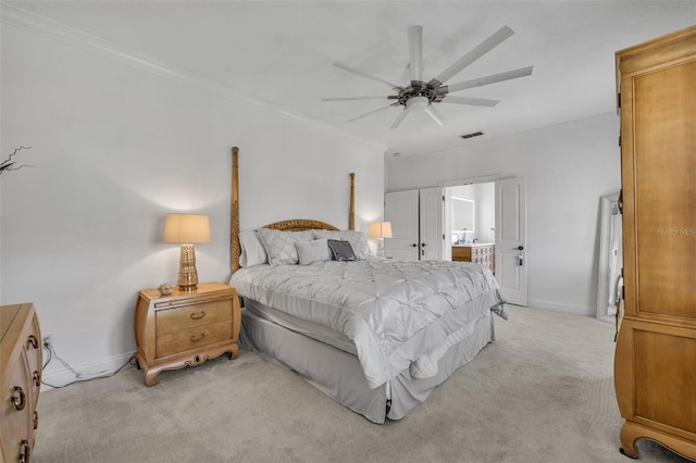 bedroom with visible vents, baseboards, light colored carpet, ensuite bath, and crown molding