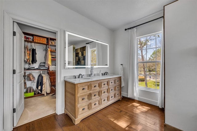 bathroom featuring double vanity, hardwood / wood-style floors, a spacious closet, and a sink