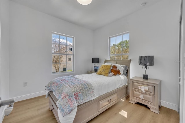 bedroom with light wood-style floors, multiple windows, and baseboards