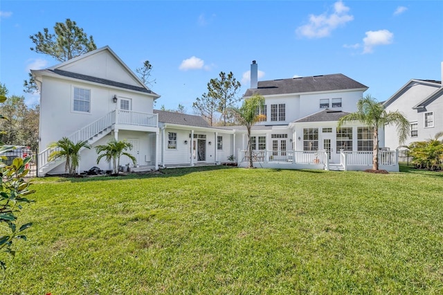 back of property with stairs, a lawn, a chimney, and a sunroom