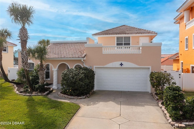 mediterranean / spanish-style home featuring driveway, fence, a balcony, and stucco siding