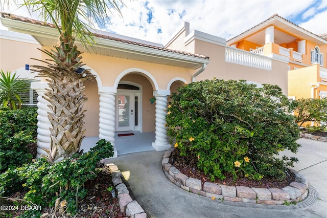 view of exterior entry with a tiled roof and stucco siding