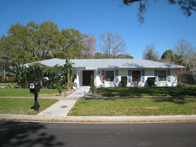 ranch-style house featuring metal roof and a front lawn