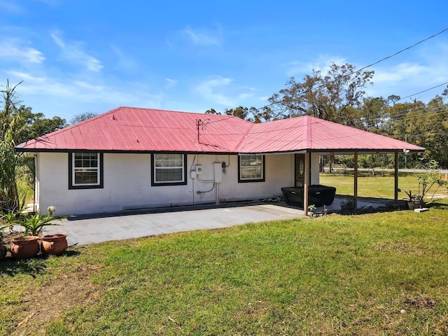 view of front of property with a front yard, stucco siding, a patio area, and metal roof