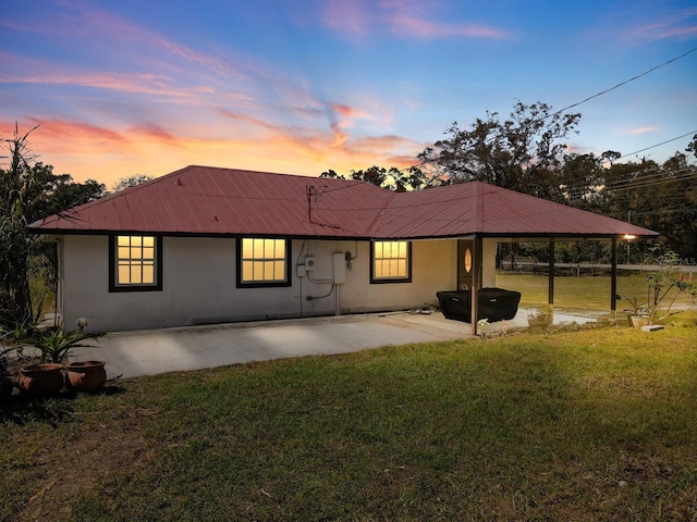 back of house featuring a yard, a patio, metal roof, and stucco siding