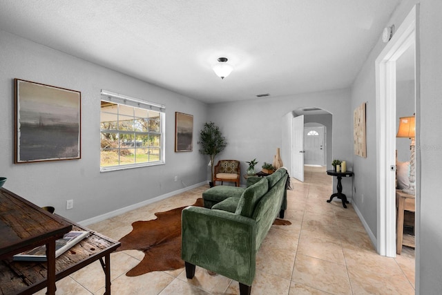 living room featuring visible vents, arched walkways, baseboards, and light tile patterned flooring