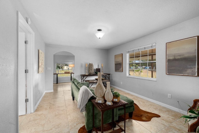 living room featuring arched walkways, plenty of natural light, and baseboards