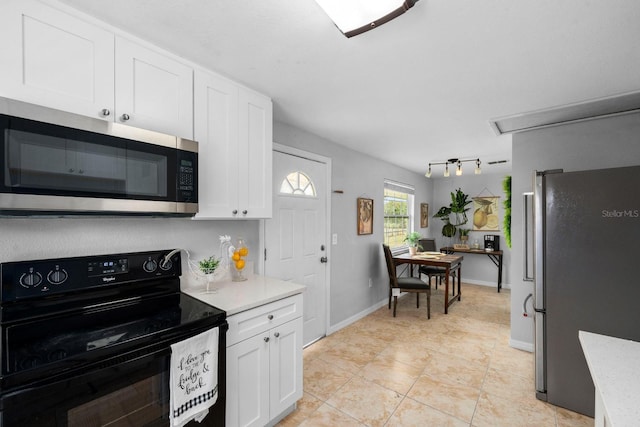 kitchen featuring light tile patterned floors, baseboards, stainless steel appliances, track lighting, and white cabinetry