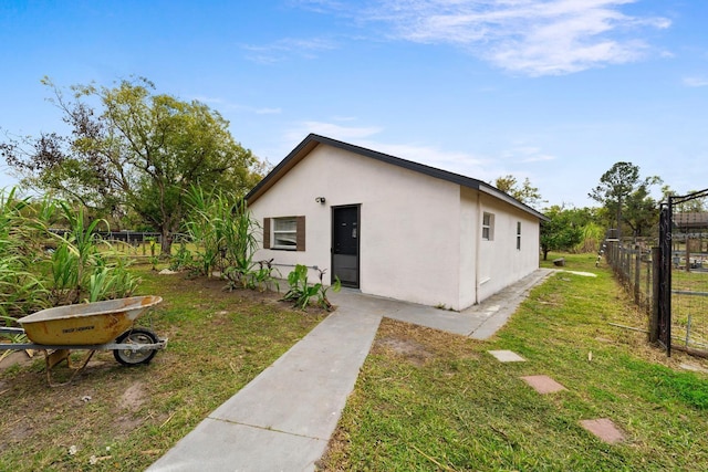 view of home's exterior with stucco siding, a yard, and fence