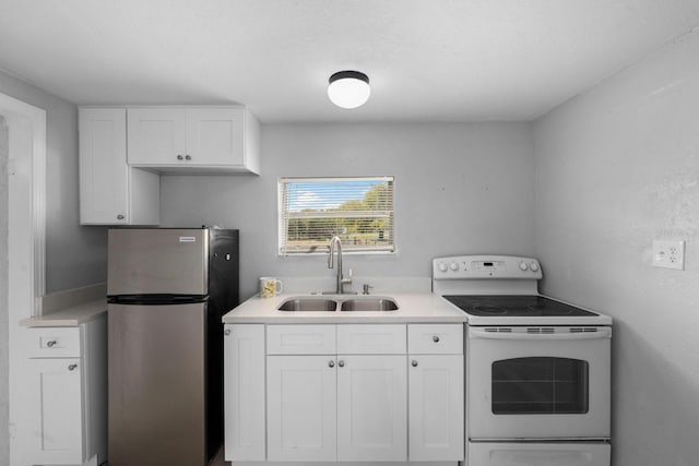 kitchen featuring electric range, freestanding refrigerator, a sink, light countertops, and white cabinetry