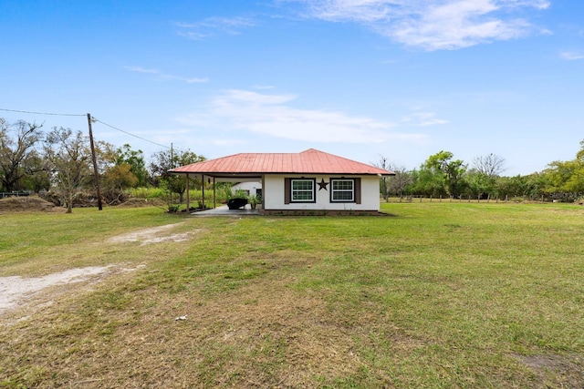 view of front of property with an attached carport, driveway, metal roof, and a front lawn