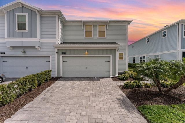 view of front of home with board and batten siding, decorative driveway, and a garage