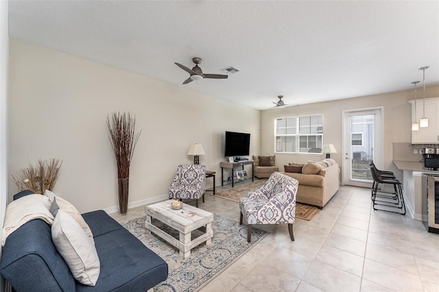 living room with light tile patterned floors, beverage cooler, a ceiling fan, and baseboards