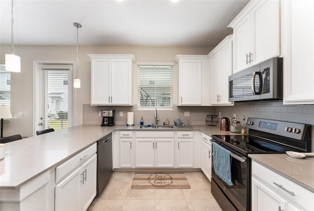 kitchen with stainless steel appliances, a sink, a peninsula, and decorative backsplash