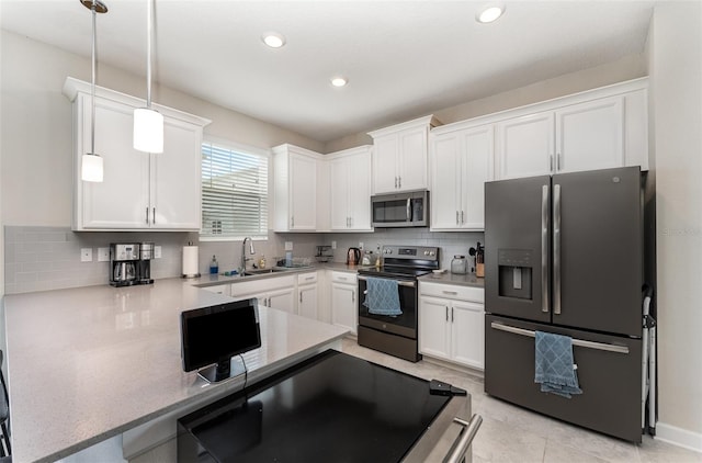 kitchen with a peninsula, white cabinets, stainless steel appliances, and backsplash