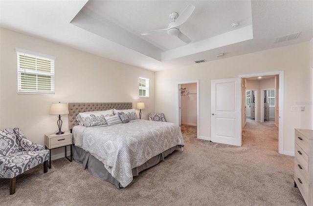 bedroom with light carpet, a raised ceiling, visible vents, and baseboards