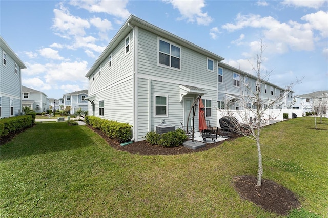 view of front facade featuring a residential view, cooling unit, and a front yard