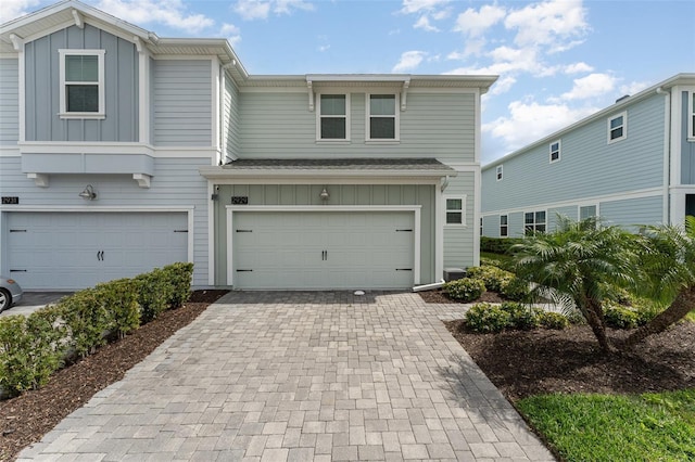 view of property featuring board and batten siding, decorative driveway, and a garage