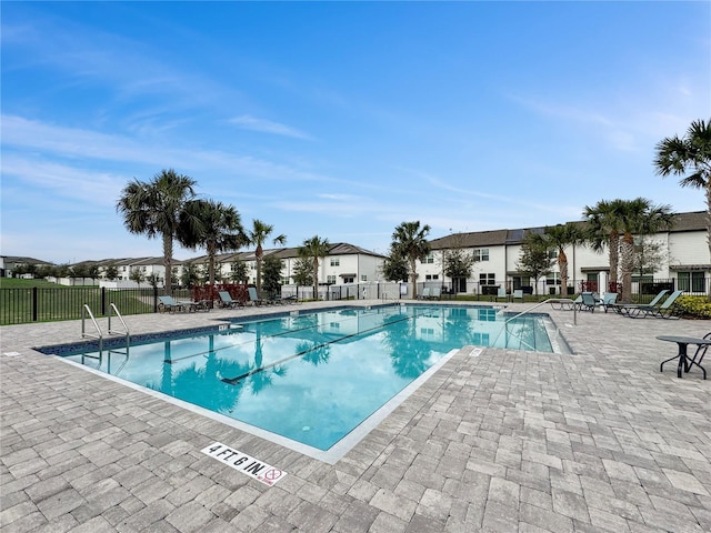 community pool with a patio area and fence