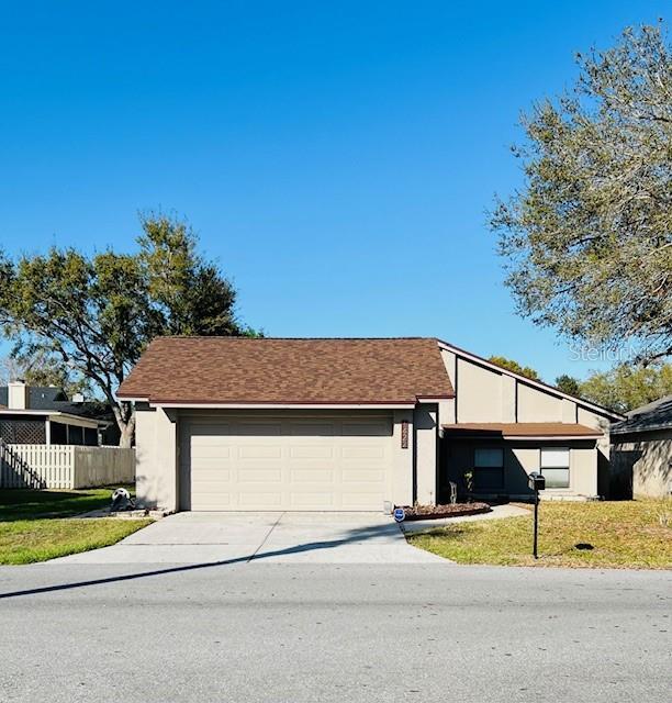 view of front of home featuring a garage, fence, driveway, stucco siding, and a front yard