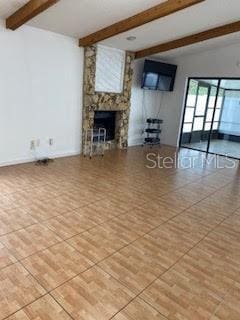 unfurnished living room featuring light tile patterned floors, a fireplace, and beam ceiling