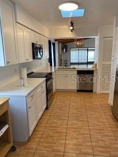 kitchen featuring light tile patterned floors, stainless steel appliances, light countertops, and white cabinets