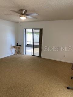 unfurnished room with a textured ceiling, a ceiling fan, and carpet flooring