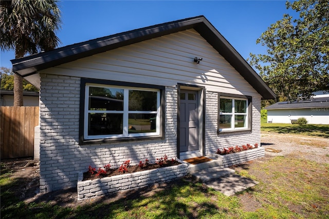 view of front of home with brick siding and fence