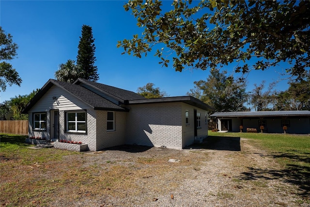 view of side of home featuring a yard, fence, and brick siding