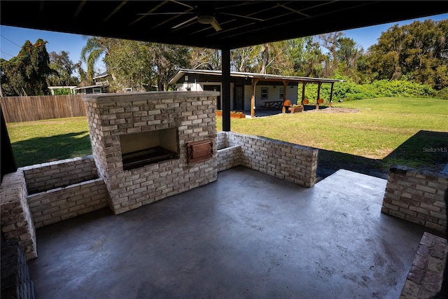 view of patio with an outdoor brick fireplace, fence, and a ceiling fan