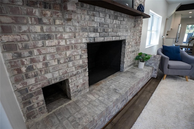 living room featuring a brick fireplace and wood finished floors