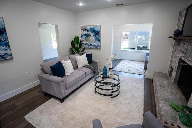 living area featuring recessed lighting, visible vents, a brick fireplace, wood finished floors, and baseboards