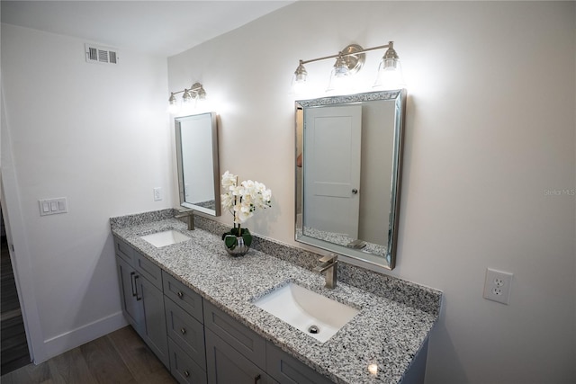 bathroom featuring double vanity, visible vents, a sink, and wood finished floors