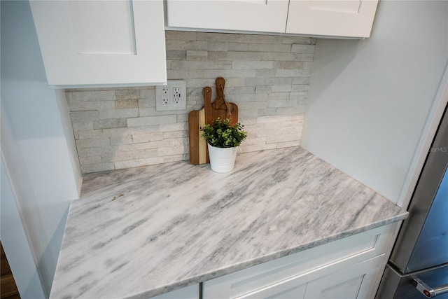 room details featuring light stone countertops and white cabinets