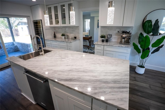 kitchen featuring stainless steel dishwasher, glass insert cabinets, dark wood-type flooring, white cabinets, and a sink