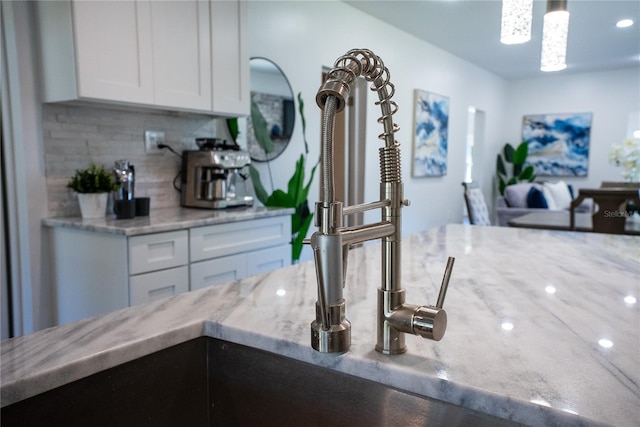 interior space featuring light stone counters, white cabinets, decorative light fixtures, and decorative backsplash