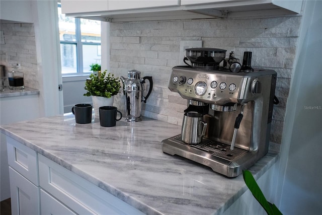 interior space featuring light stone counters, white cabinets, and backsplash